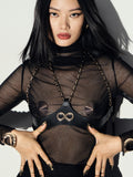 Model wearing the vegan leather Aria Crossed Bra over a black sheer outfit against a neutral background